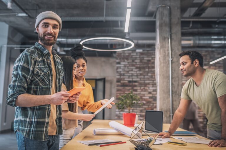 Bearded guy with tablet and colleagues in office