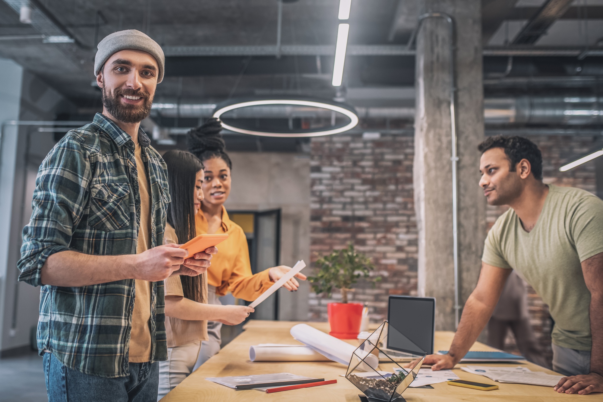 Bearded guy with tablet and colleagues in office