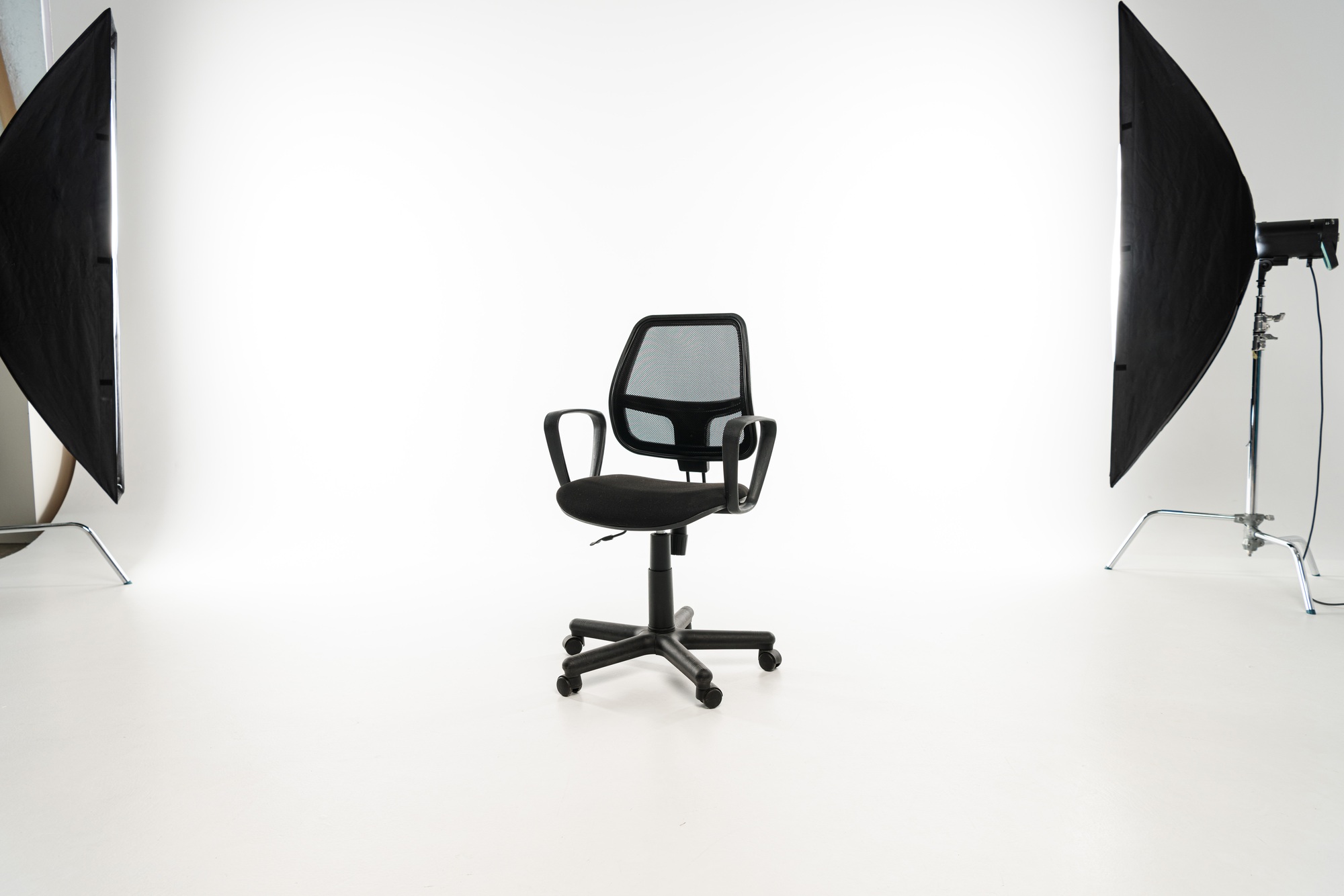 Black office chair with studio light on white background