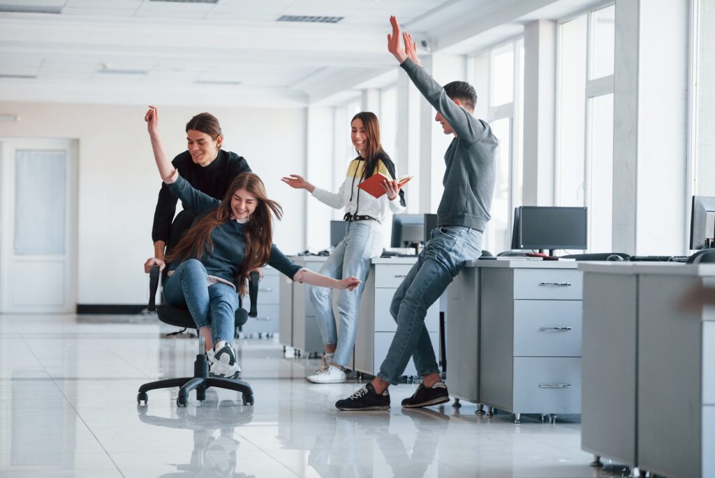 Having fun in the office. Young people have a break and driving by using a seat
