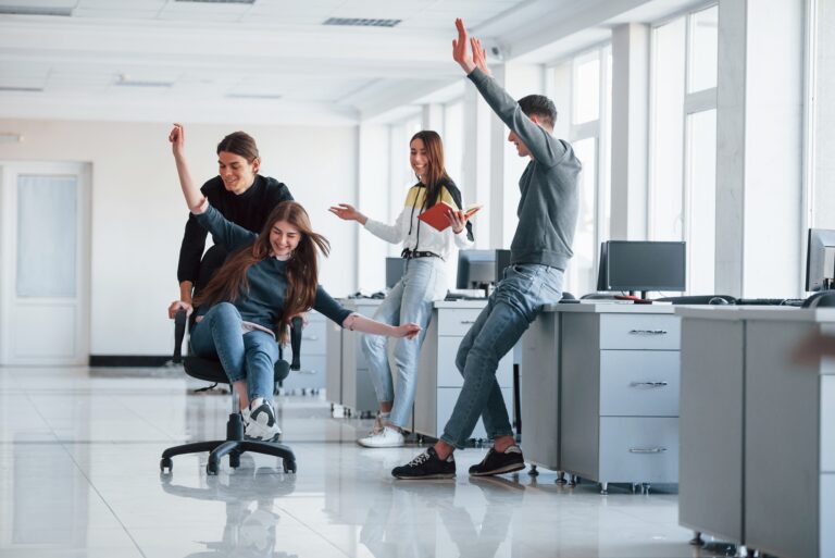 Having fun in the office. Young people have a break and driving by using a seat
