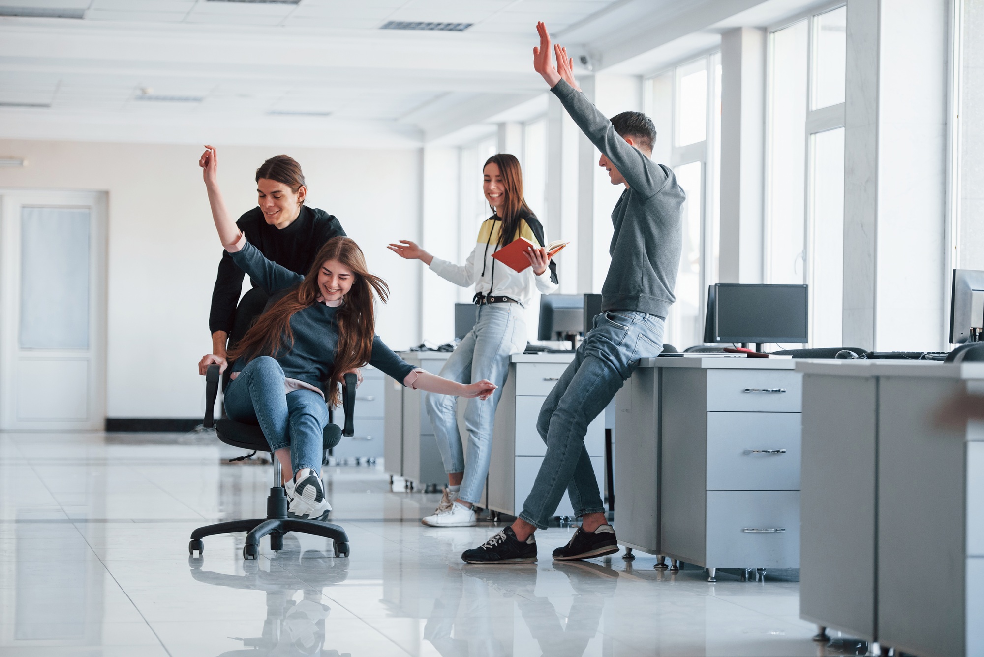 Having fun in the office. Young people have a break and driving by using a seat