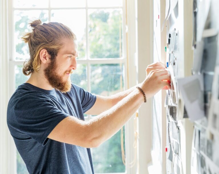 Young male designer pinning mood board ideas to wall in creative studio