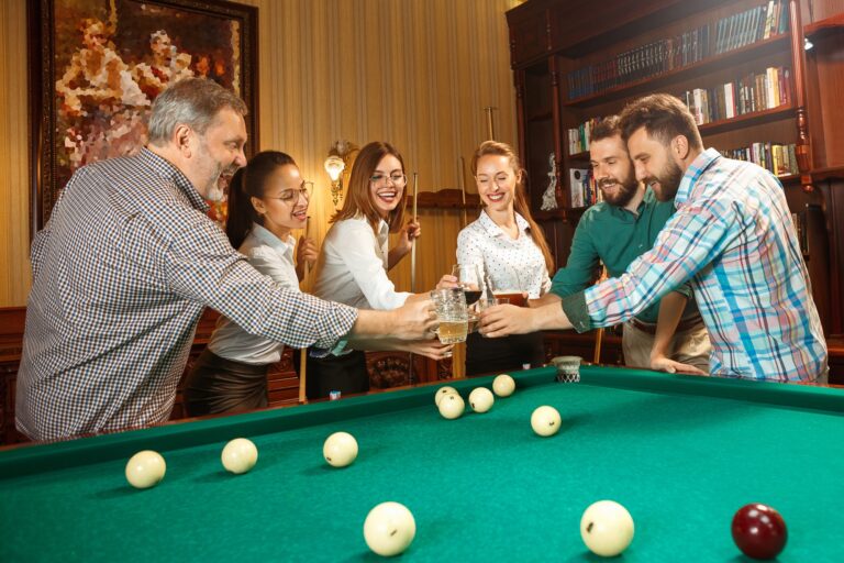 Young men and women playing billiards at office after work.