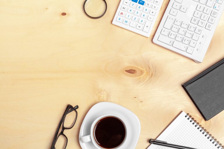 Office table with note paper, computer keyboard and supplies close up